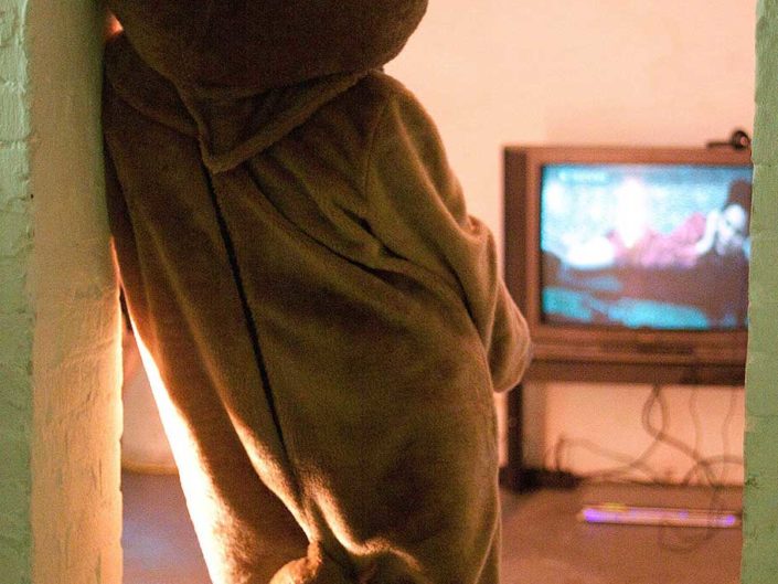 Persona disfrazada de oso mirando la televisión