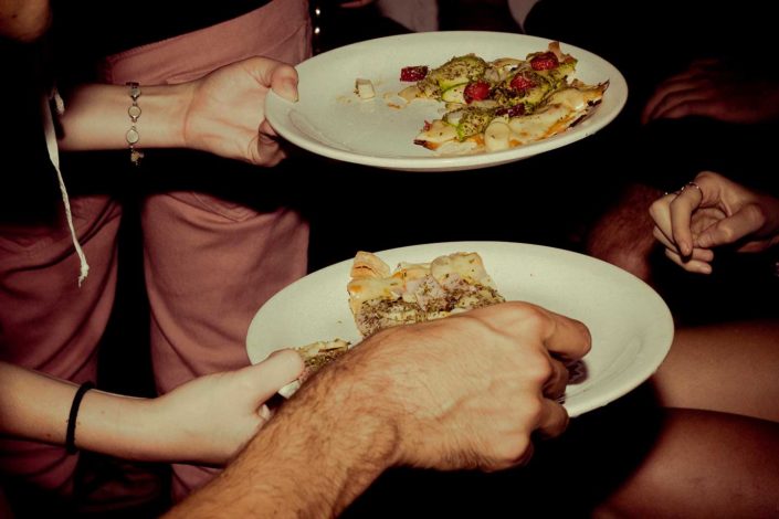 Manos de personas cojiendo pizza de un plato