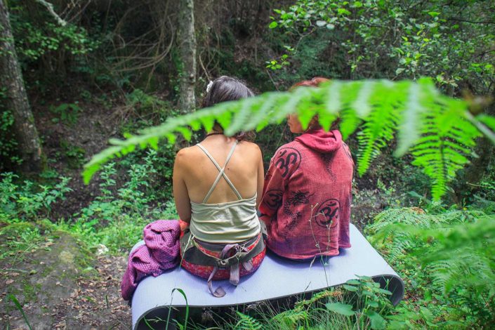 Dos mujeres sentadas en un banco en medio del bosque hablando