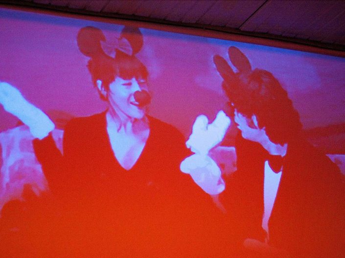 Poryección en la pared de un hombre y una mujer disfrazados de Minie y Mickey Mouse