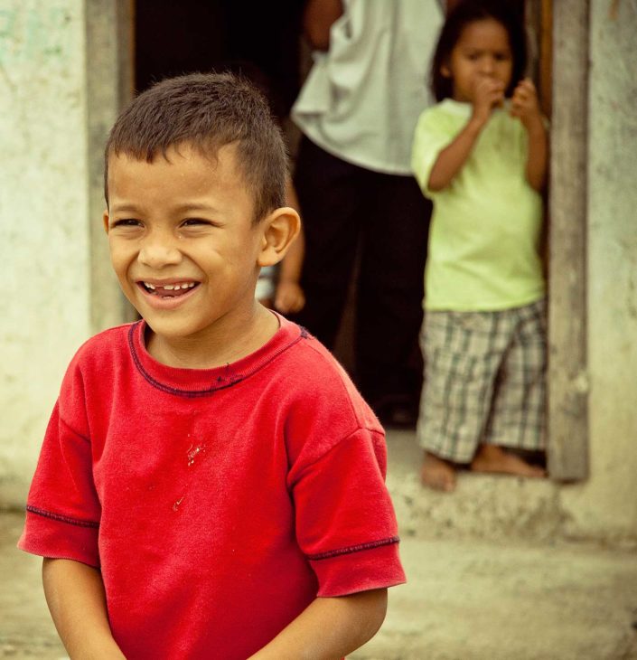 Niño sonriendo, detrás un niño sale de una puerta