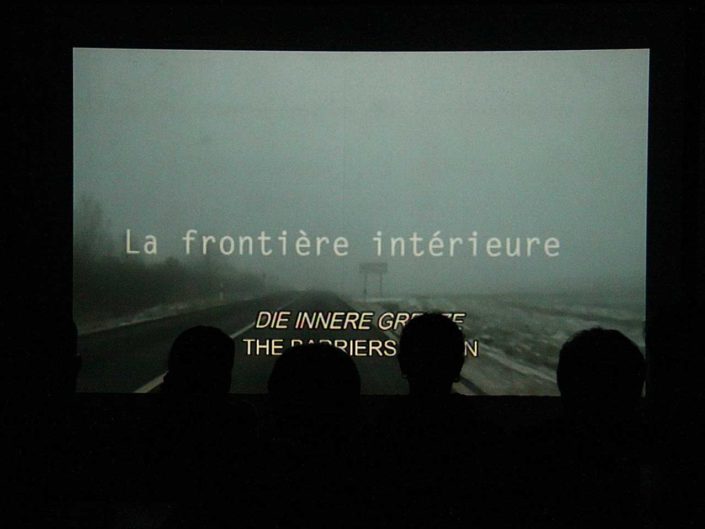 Poryección de película en la pared y siluetas de los espectadores