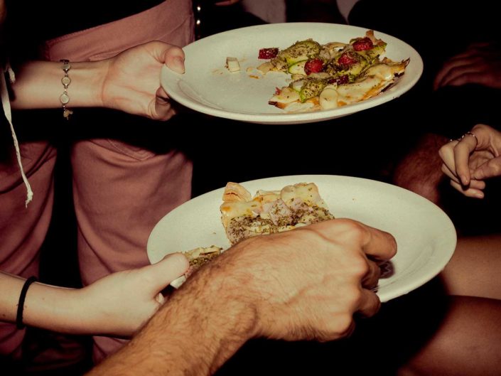 Manos de personas cojiendo pizza de un plato
