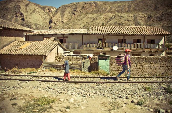 Casas, vías del tres, un niño y una mujer andando.