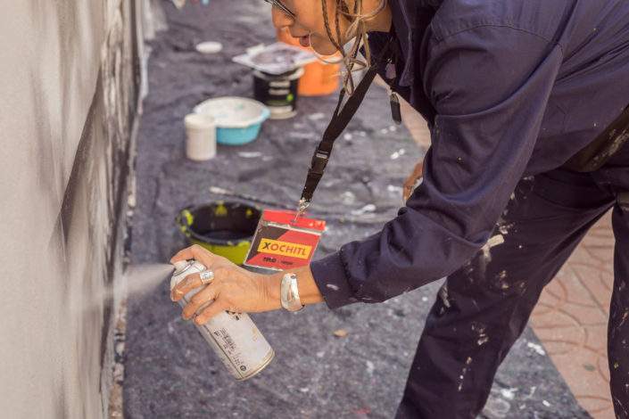 Mujer artista pintando un muro con spray